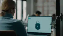 Image d'une personne assise à son poste de travail avec un cadenas de sécurité au premier plan, indiquant l'importance de sécuriser les postes de travail.